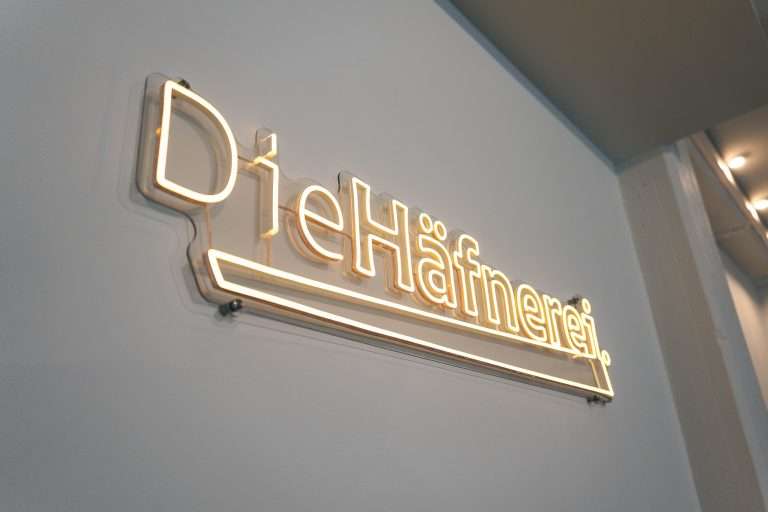Kreativraum Die Häfnerei in Würzburg, beleuchtetes Logo an der Wand