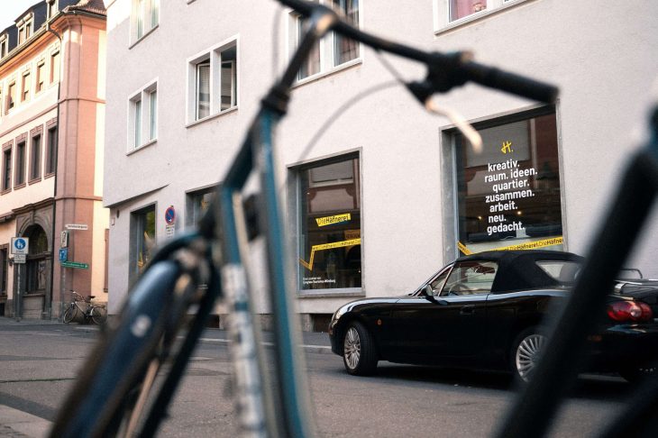 Außenansicht des Kreativraumes - Die Häfnerei in Würzburg mit Schaufenster, geparktem Cabrio und unscharfem Fahrrad im Vordergrund.
